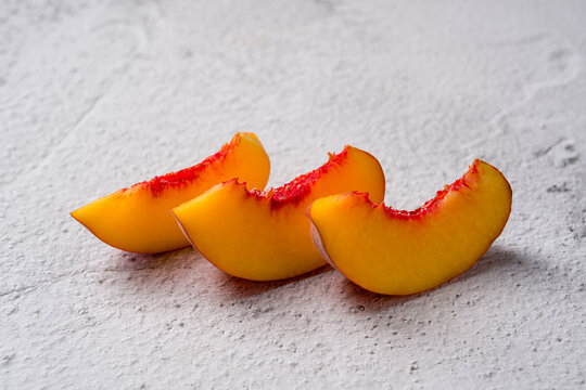 Three fresh peach slices placed on a white textured surface