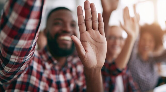 Diverse group of smiling people raising hands in celebration, showing joy and engagement in a bright, modern setting