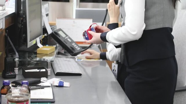 사무실에서 직원이 업무용 물품을 정리하며 통신 장비와 서류 등을 확인하는 모습입니다.