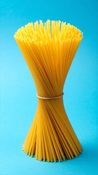 Raw Spaghetti Bundle Tied with String on Bright Blue Background - Minimalist Food Concept