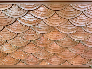 Decorative terracotta surface with a scalloped pattern resembling fish scales or traditional asian Japanese waves. © TMR Studio