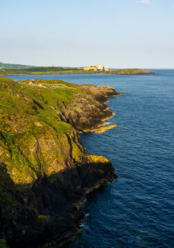 The rocky cliffs of Cemaes Bay overlook the Irish Sea with the distant Wylfa Nuclear Power Station on the Anglesey coast of North Wales.