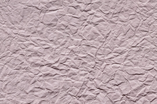 Crumpled light pink paper texture background with wrinkles for creative design projects