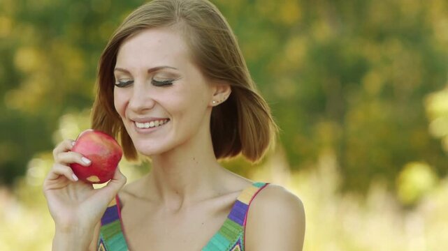 Young beautiful woman eating ripe red apple