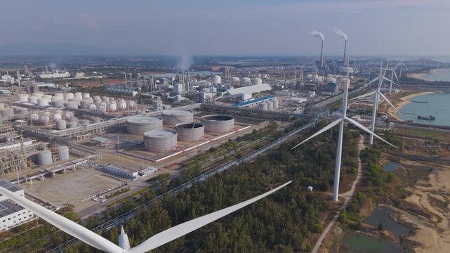 Aerial footage of wind turbines on the coast of Dongfang city, Hainan Island, with petrochemical factory in the background.