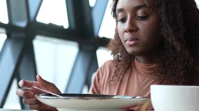 Beautiful African American woman eating pasta with seafood in a restaurant. Woman enjoying food. Close-up