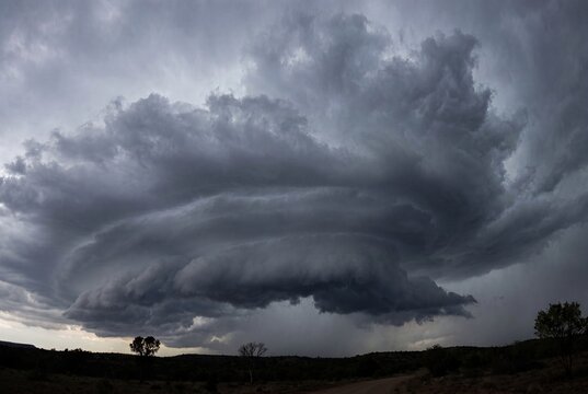 A dramatic swirling storm cloud looms over a barren landscape. Dark gray clouds create a menacing atmosphere, hinting at an impending storm.