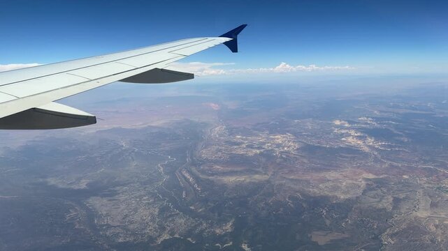 Airplane Wing Above Epic Utah Nevada Mountain Range. View Through Plane Window Passenger 747 Silver and Blue Tip. National Park Aerial Flight