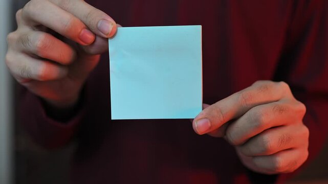 Close Up of Hands Holding Blank White Sticky Note with Copy Space