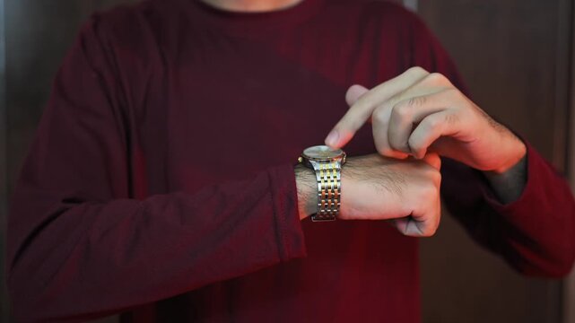 man sits on a sofa and looks at his wristwatch. The man is in a hurry and is keeping track of time