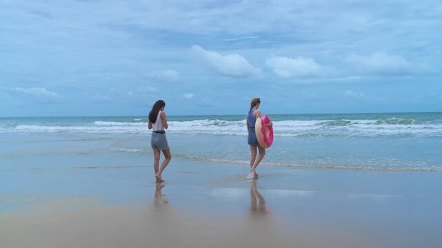 Two women walking with an inflatable ring, experiencing the slow living and stress relief of a peaceful, unplugged weekend getaway.