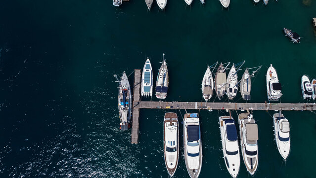 Top-down aerial drone view of a small boat moving smoothly across crystal clear blue ocean water, leaving white waves behind. Luxury tropical travel and summer vacation concept. Gozo, Mgarr, Malta.