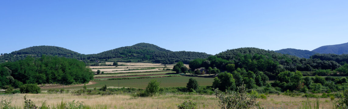 Panoramic rural landscape of La Garrotxa volcanic region in Catalonia, Spain. Fields, forests and rounded volcanic hills near Santa Pau and Olot.