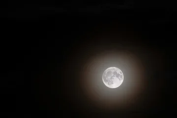 full moon glowing through dark night sky © taviphoto