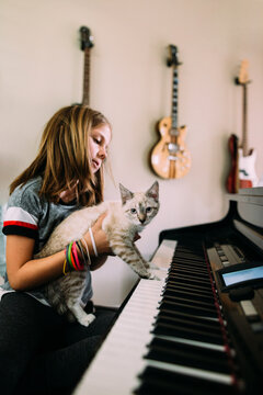 girl playing piano with kitten 