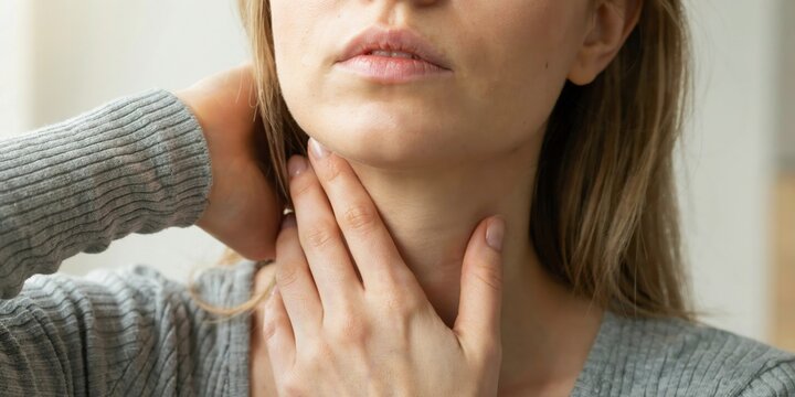 Woman touching her sore throat or thyroid gland feeling pain and discomfort due to illness or infection.