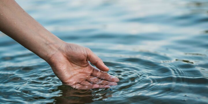 Close up of hand touching clear water surface.