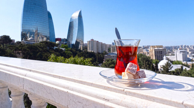 Traditional Azerbaijani black tea served in an elegant armudu glass with a scenic Baku cityscape in the background, blending local culture with urban charm.