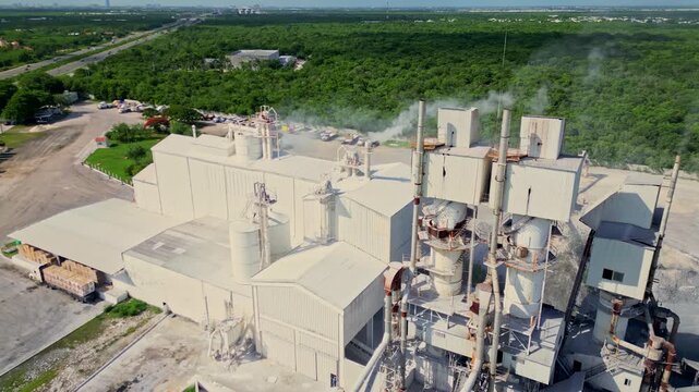 Aerial orbiting view of a lime kiln factory emitting smoke