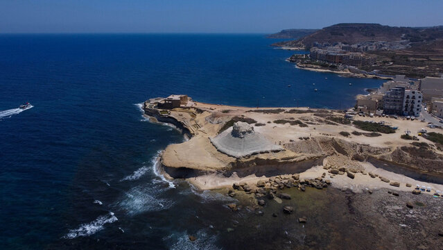 Xwejni s centuries-old salt pans unfold along the rugged coast of Zebbug, Gozo, geometric pools and vivid Mediterranean blues in a sweeping summer Aerial view
