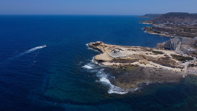 Xwejni s centuries-old salt pans unfold along the rugged coast of Zebbug, Gozo, geometric pools and vivid Mediterranean blues in a sweeping summer Aerial view