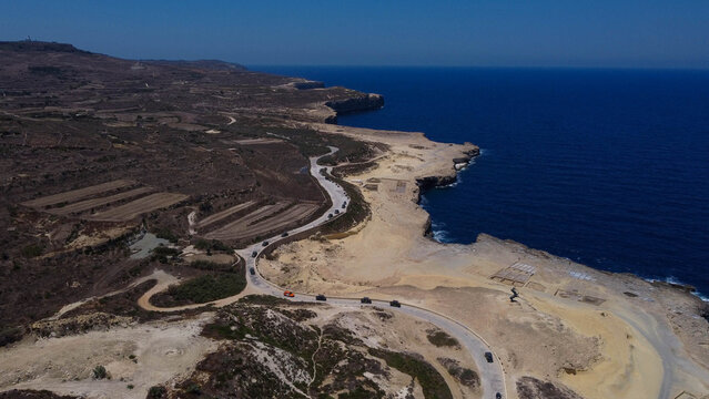 Xwejni s centuries-old salt pans unfold along the rugged coast of Zebbug, Gozo, geometric pools and vivid Mediterranean blues in a sweeping summer Aerial view