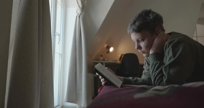 Caucasian Boy Kid Read Bible Book Lying on Bed in Bedroom. 4K 10-bit