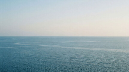 Fototapeta premium The scene shows a vast ocean stretching to the horizon. The sky is light with few clouds. The water is smooth. This is a quiet morning on the coast.