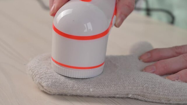 A woman revives the look of her knitted garments with a lint remover.