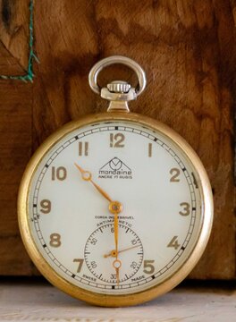 Brazil, December 26, 2016: vintage Mondaine pocket watch with gold-tone case, cream dial, and small seconds subdial, displayed against a rustic wooden background.