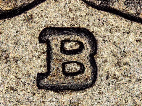 Microscopic view of engraved letter B on Swiss franc coin under microscope