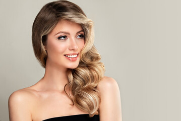 Beautiful laughing blonde model girl with long curly hair . Smiling woman hairstyle wavy curls . Fashion , beauty and makeup portrait  © Sofia Zhuravetc