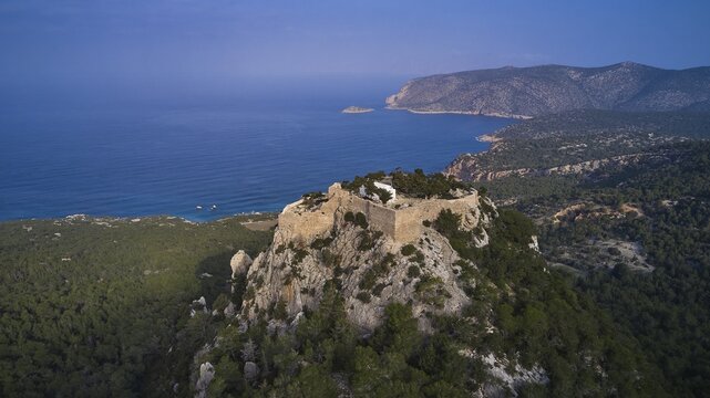 An ancient castle on a rocky peak surrounded by a forest overlooking the calm blue sea and the coastline, Kastro Monolithou, Monolithos Castle, Monolithos Rock Castle, Monolithos Village, Rhodes, Dodecanese, Greek Islands, Greece