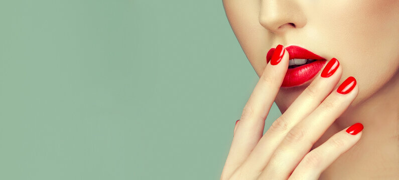 Beautiful girl showing red manicure nails . Beauty woman Red lips , makeup and cosmetics
