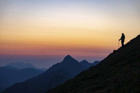 Mountaineer on mountain ridge with Rothorn peak in the background at blue hour, Interlaken, Bernese Oberland, Switzerland