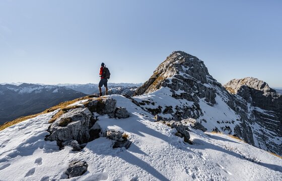 Climbers on the rocky summit ridge with first snow in autumn, hiking trail to Guffert, solar reflex, Brandenberg Alps, Tyrol, Austria