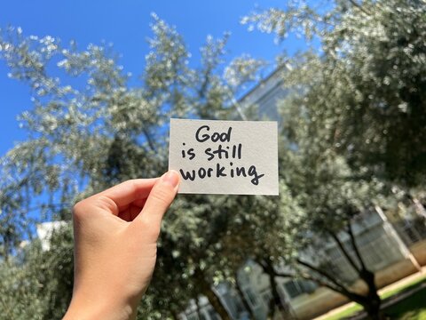 Hand with christian note - God is still working, religion concept