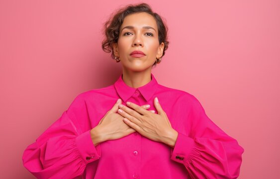 A South African woman in her mid 30s stands with arms crossed at chest height, showcasing a bold feminine look in a warm light setting