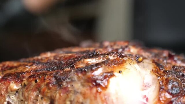 A detailed close-up shot of a perfectly grilled barbecue steak, highlighting the tender, juicy meat fibers and the rich, seared crust. The footage captures the steam and glistening texture of a premiu