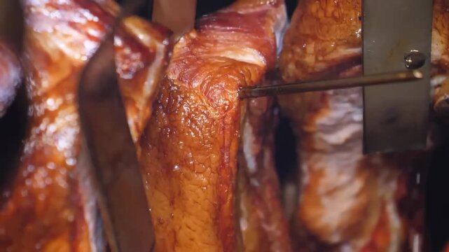 High-quality close-up footage of marinated pork steaks or belly meat roasting in a traditional smokehouse. The video captures the glistening fat, dark caramelized crust, and savory textures of the mea