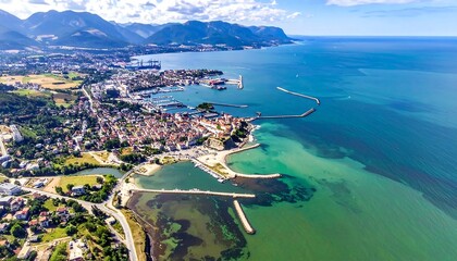 Obraz premium Aerial view of a coastal town with a harbor and mountains