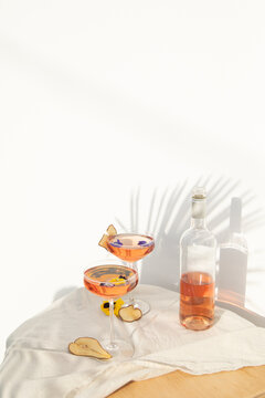 Two rose wine glasses with summer cocktails and dried fruit appetizers