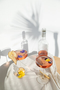 Two rose wine glasses with summer cocktails and dried fruit appetizers