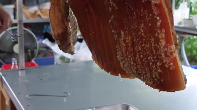 A close-up shot showcasing the crunchy, crackling texture of freshly roasted pork belly. The footage features succulent, juicy meat with a perfectly golden-brown, crispy skin being handled on a silver