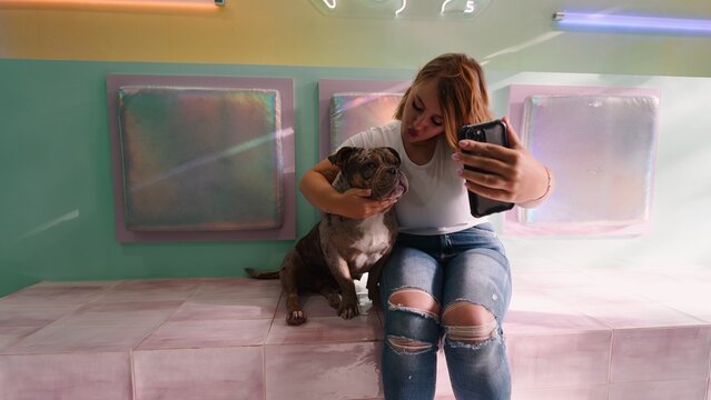 Young woman making a duck face for a selfie with her bulldog
