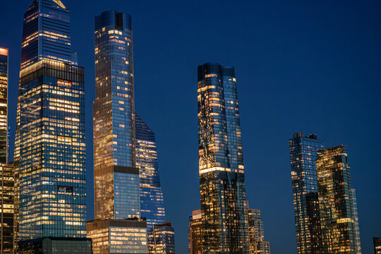 Hudson Yards towers with open night sky in Manhattan. Glass skyscrapers occupy the left and lower frame, leaving broad blue copy space above the city.