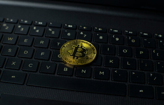 Bitcoin coin placed on a laptop keyboard, representing online finance, crypto trading, blockchain payment, digital asset