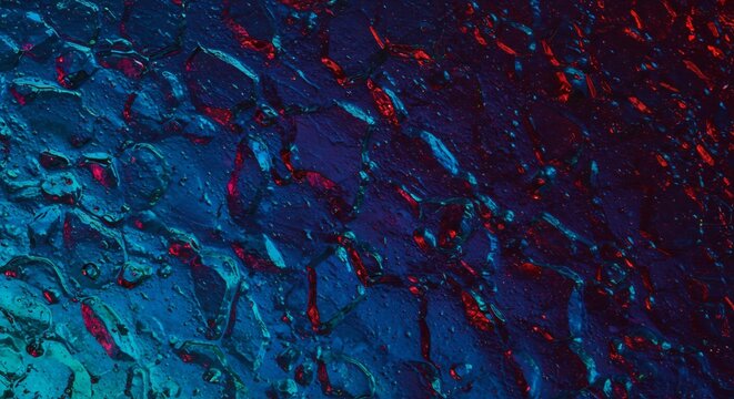 Molten blue and crimson light flowing across a dark textured abstract background capturing intense reflections. AI Generated