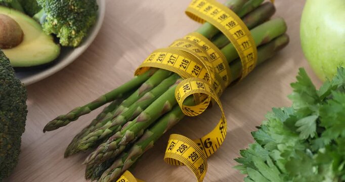 Measuring tape and healthy products on wooden table, zooming in
