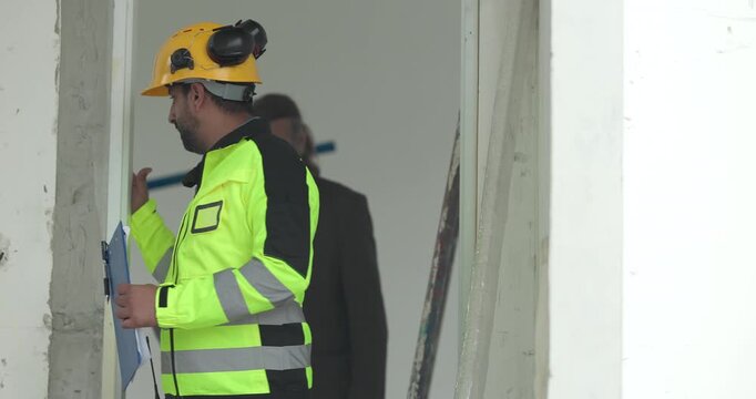 Engineer and businessman inspecting house construction site while discussing building project